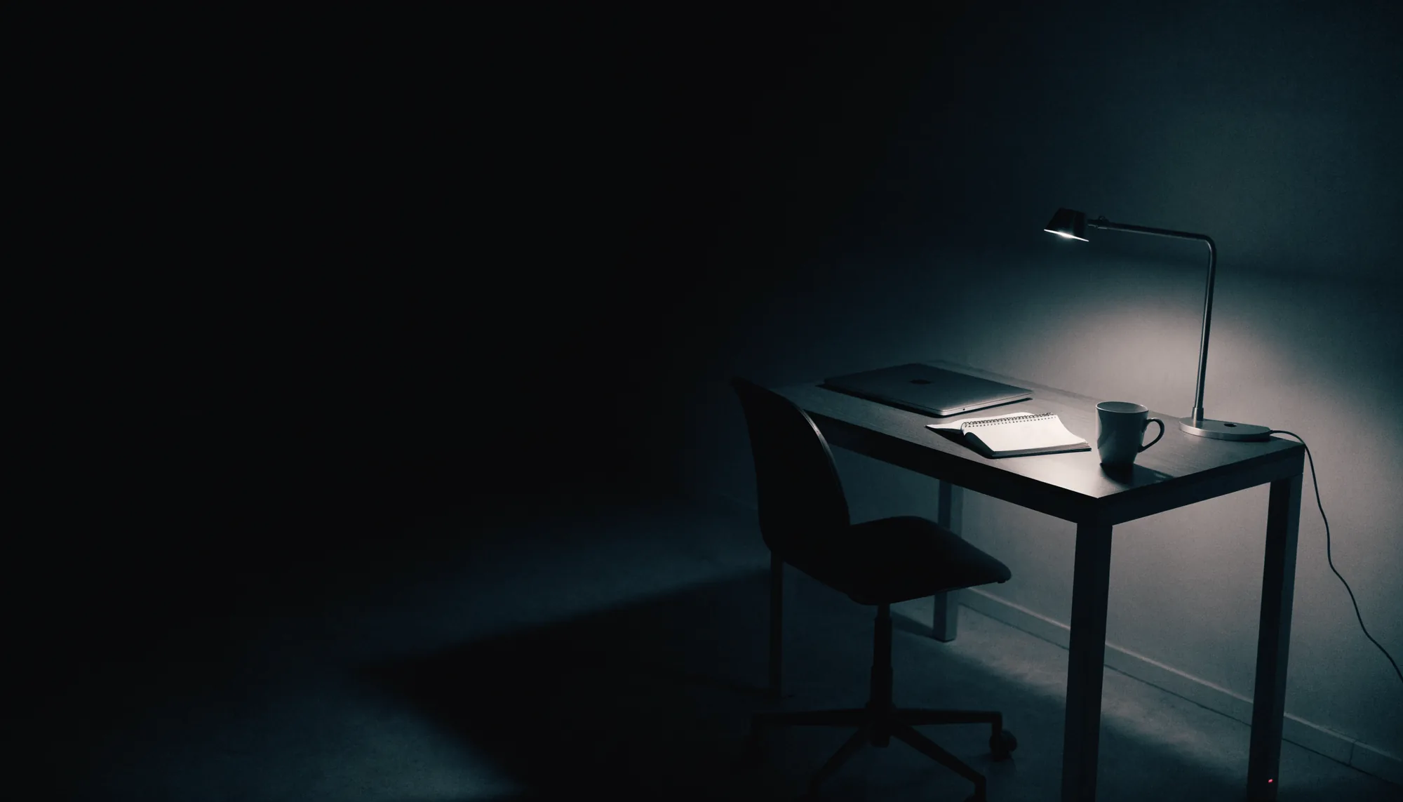 Un escritorio de trabajo ordenado y en silencio, con una sola lámpara encendida y sin nadie: el trabajo remoto
